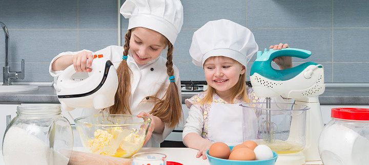 Zwei Mädchen hantieren mit Küchenmaschinen